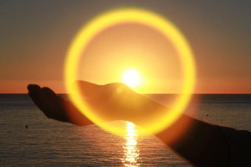 Manos abiertas hacia el sol, sobre el mar